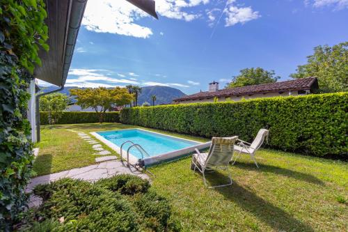 a backyard with a swimming pool and two chairs at Villa Calella - Happy Rentals in Magliaso