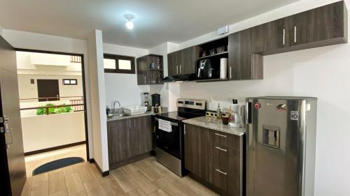 a kitchen with wooden cabinets and a stainless steel refrigerator at Apartamento en centro Ciudad de Guatemala z12 in Guatemala