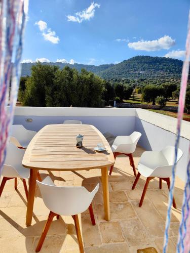 een houten tafel en witte stoelen op een balkon bij Masseria Celeste in Fasano