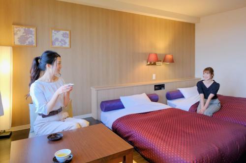 two women in a hotel room with two beds at Morinoyu Hotel Hanakagura in Asahikawa