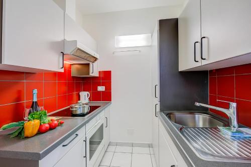 una cocina con armarios blancos y azulejos rojos en Locarno Best Place - Happy Rentals, en Locarno