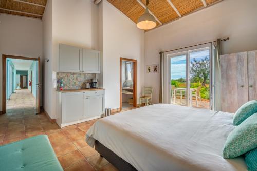a bedroom with a large bed and a kitchen at Quinta das Piteiras-Turismo Rural in Silves