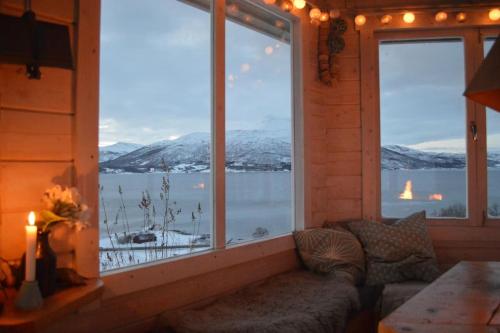 a living room with a couch in front of a large window at Aurora panorama 2nd floor in Laksvatn