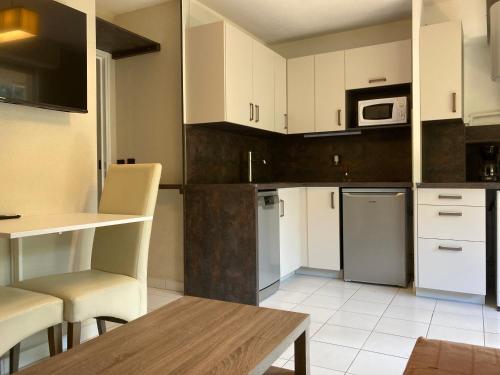 une cuisine avec des armoires blanches et des appareils électroménagers blancs dans l'établissement Saphir de Collioure, à Collioure