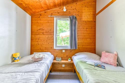 two beds in a room with a window at Camping LA SERRE in Aigues-Vives