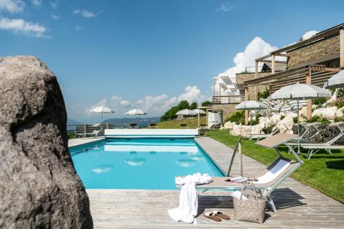 einen Pool in einem Hotel mit Stühlen und Sonnenschirmen in der Unterkunft Hotel Valentinerhof in Seis am Schlern