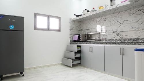 eine Küche mit weißen Schränken und einer Steinmauer in der Unterkunft Hotel apartment america in Ad-Dakhla