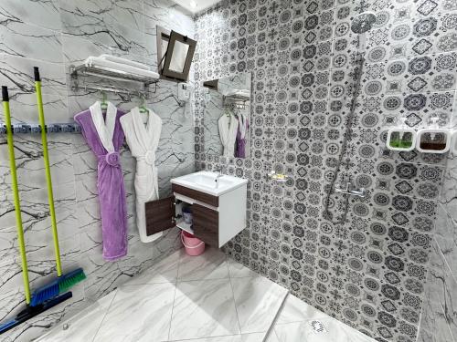 La salle de bains est pourvue d'un lavabo, d'une douche et de peignoirs violets. dans l'établissement Hotel apartment america, à Dakhla