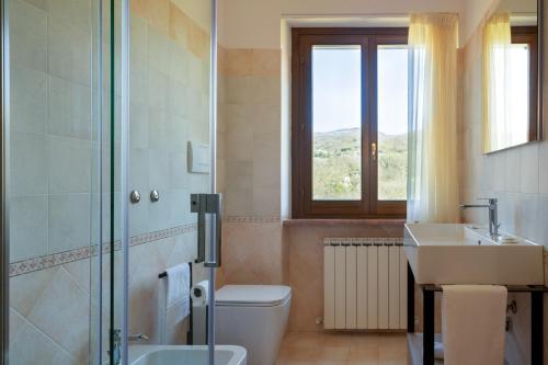 a bathroom with a toilet and a sink and a window at Relais Parco Del Subasio in Piano Delle Pieve