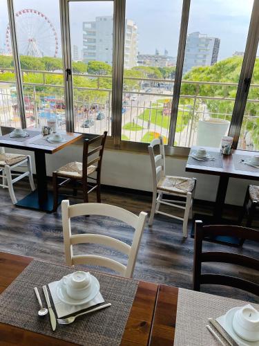 een restaurant met tafels en stoelen en uitzicht op een reuzenrad bij Hotel Cristina in Lido di Jesolo