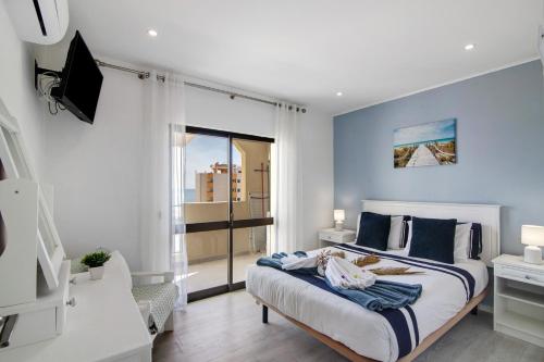 a bedroom with a bed with blue walls and a window at Luxury Beach View - Praia da Rocha in Portimão