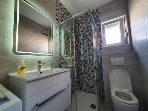 een badkamer met een wastafel, een toilet en een raam bij Apartman Sunce in Kaštela