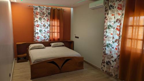 1 dormitorio pequeño con cama y cortinas en Clarisse Lodge, en Lomé
