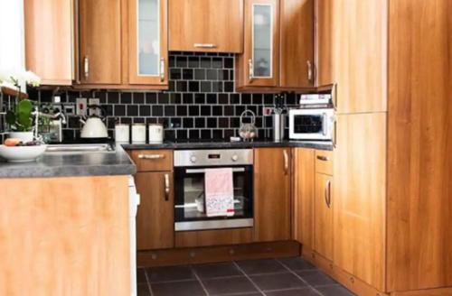 a kitchen with wooden cabinets and a stove top oven at Stone Cottage. Full of character barn conversion Pass the Keys in Highley