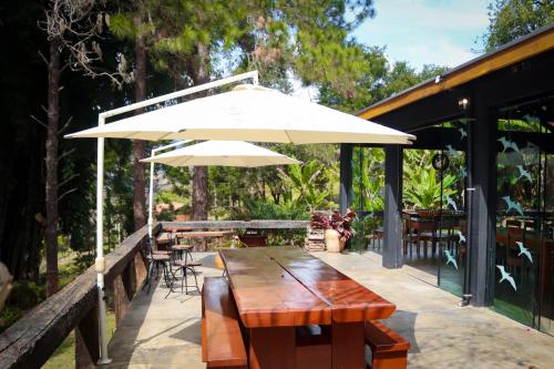 - une table en bois avec un parasol sur la terrasse dans l'établissement Pousada Vidinha Bela, à Brazópolis