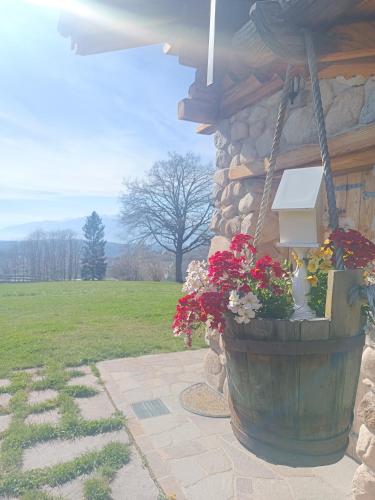 a wooden barrel with flowers in a stone building at Baita dei Fovi in Baselga di Pinè