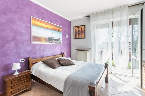 a bedroom with a bed and a purple wall at Lilly House - Travacò Siccomario - by HOST4U in San Martino Siccomario