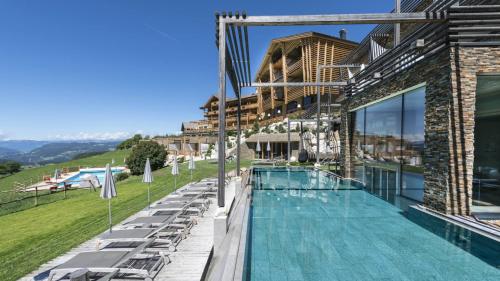uma piscina com espreguiçadeiras e um edifício em Hotel Valentinerhof em Siusi