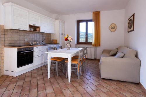 a kitchen and living room with a table and a couch at Relais Parco Del Subasio in Piano Delle Pieve