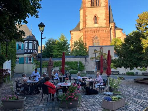 a group of people sitting at tables in front of a church at Romantikurlaub im Weindorf Kiedrich in Kiedrich