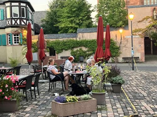 a group of people sitting at a table with umbrellas at Romantikurlaub im Weindorf Kiedrich in Kiedrich