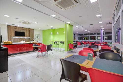 a restaurant with red chairs and tables and a green wall at Go Inn Cambuí Campinas in Campinas