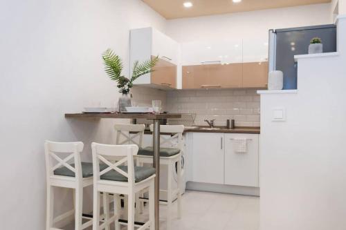 a kitchen with white cabinets and white stools at Perfect place in the heart of downtown in Budapest