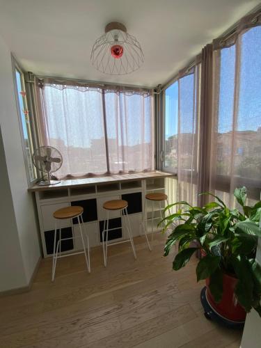 a room with a desk and stools in front of windows at Chez virginie : Appartement lumineux au calme. in Fréjus