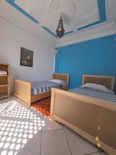 2 camas en una habitación con paredes azules en CampSurf Morocco, en Tamraght Ouzdar