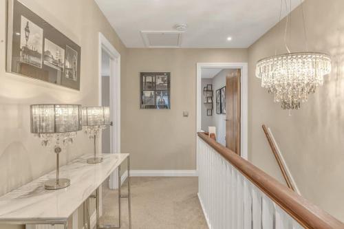 a white hallway with a chandelier and a staircase at Foxglove House in Loughborough