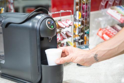 a hand holding a coffee cup next to a coffee machine at Transamerica Fit Campinas in Campinas