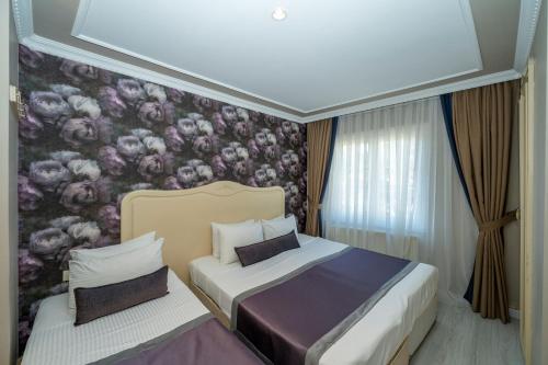 a bedroom with two beds and a floral wallpaper at Raymond Hotel in Istanbul