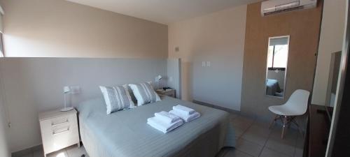 Un dormitorio blanco con una cama con toallas. en Espectacular ubicación con terraza propia en Mendoza
