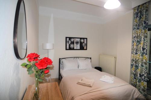 - une chambre avec un lit et un vase avec des fleurs rouges dans l'établissement Georgia's lakeside house, à Kastoria