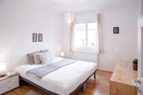 a white bedroom with a large bed and a window at Stylish and comfy apartment for 6 guests in Budapest