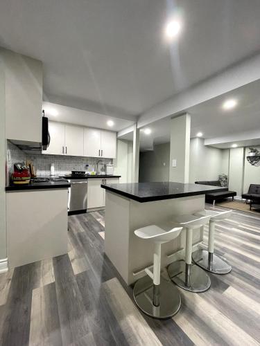 a large kitchen with a black counter and stools at Niagara Falls BNB 15 mins away from Falls in Thorold