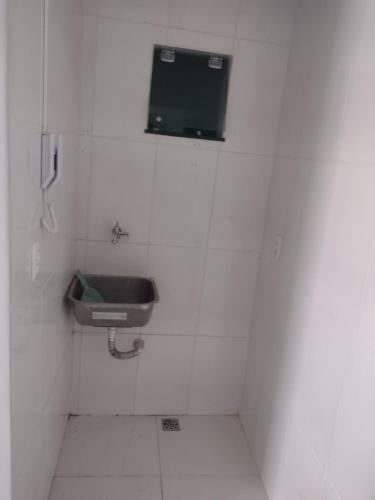 uma casa de banho com um lavatório e uma televisão na parede em Kitnet mobiliado em Belém