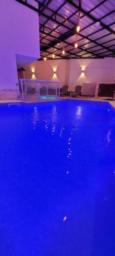 a large blue swimming pool in a building with lights at Immeuble Thala Duplex in Tigzirt