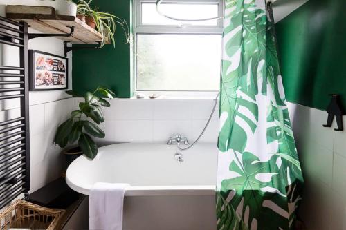 a bathroom with a white tub and a green shower curtain at Hygge House Cosy 3 Bedroom 2 Bathroom Townhouse in Kegworth
