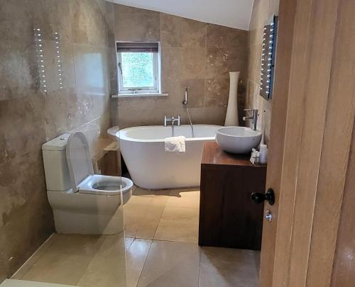 La salle de bains est pourvue d'une baignoire, de toilettes et d'un lavabo. dans l'établissement Woodlands, à Windermere