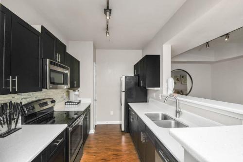 La cuisine est équipée de placards noirs et d'un réfrigérateur en acier inoxydable. dans l'établissement Cozy retreat getaway Family-sized By Lake Eola, à Orlando