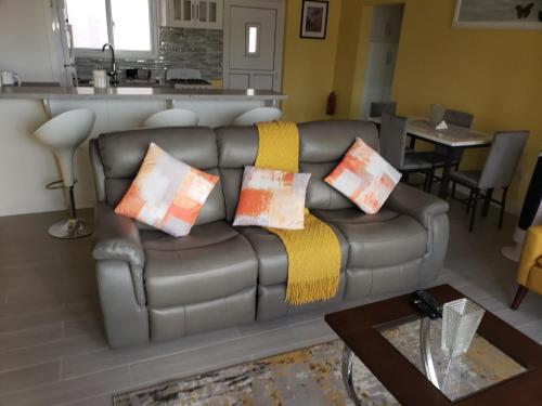 a living room with a leather couch with pillows on it at JEMMROSE SUITES in Choc