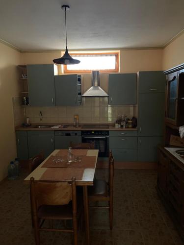 una cucina con tavolo, sedie e luce di Kuća na selu ANNA a Feketitsch
