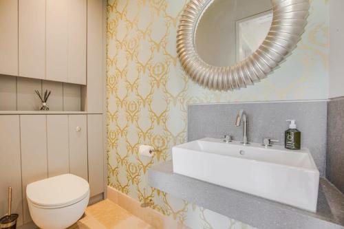 een badkamer met een wastafel, een toilet en een spiegel bij Washbrook Cottage - Hot Tub Packages Available in Little Compton
