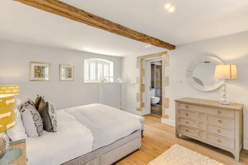 a bedroom with a bed and a dresser and a mirror at Washbrook Cottage - Hot Tub Packages Available in Little Compton