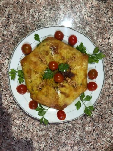 a plate with a piece of food with tomatoes on it at Hotel camping le Soleil Tinghir in Tinerhir