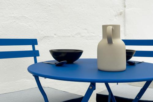 een blauwe tafel met twee kommen en een fles erop bij Setúbal Terrace apartments in Setúbal