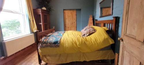 a bedroom with a bed with a yellow blanket at The Manse featuring the Daisy Camrose in Haverfordwest