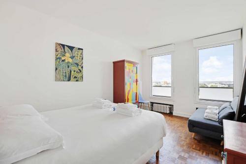 um quarto com uma cama, um sofá e 2 janelas em Amazing panoramic view facing Parc de La Villette - Apartment 4P em Paris