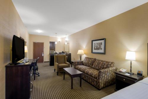 a hotel room with a couch and a television at Best Western Sunrise Inn & Suites in Stony Plain